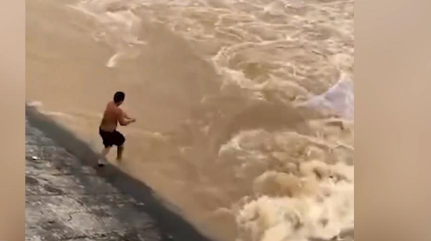 男子在洪水汹涌时候撒网捕鱼，不小心被洪水冲走